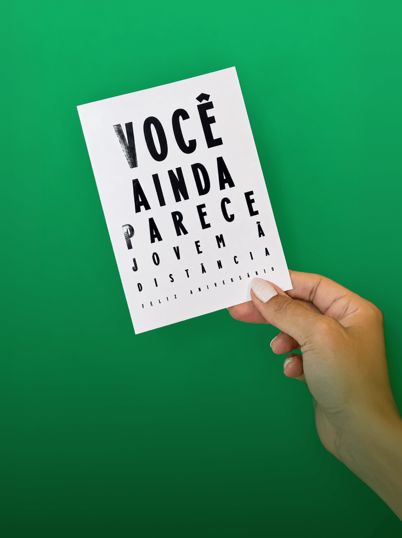 Mãos segurando o cartão New Year Same Bitch sobre fundo verde