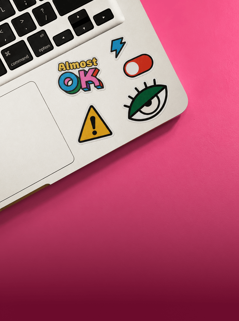 Notebook prateado coberto de stickers Certified Shiit sobre fundo rosa